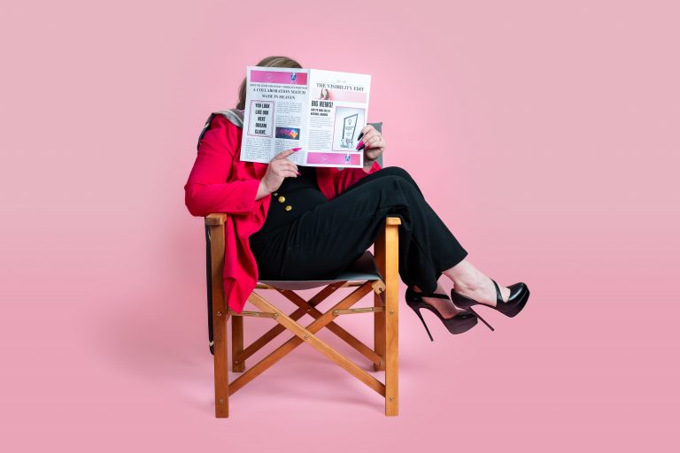 Shh! PR founder Amie-Leigh sat sideways on a director chair's, hiding behind a newspaper