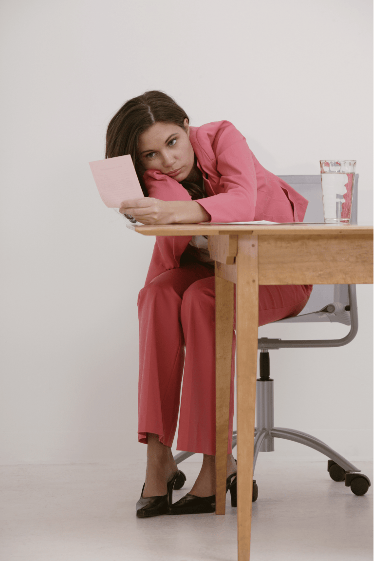 A female business owner sat at her desk with her head on her arm looking at a piece of paper